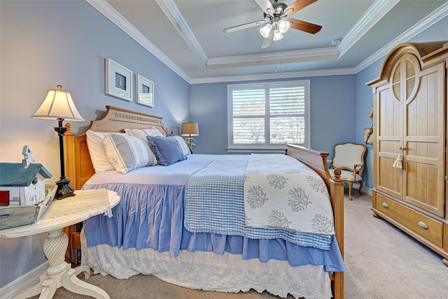 carpeted bedroom featuring ceiling fan, crown molding, and a tray ceiling