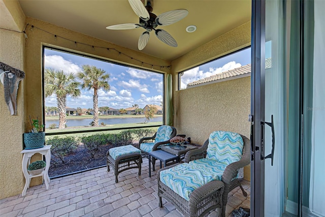 sunroom / solarium featuring a water view and ceiling fan