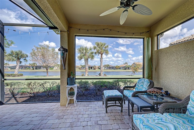 sunroom featuring a water view and ceiling fan