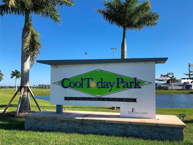 community / neighborhood sign featuring a water view and a lawn