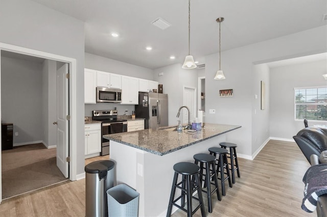 kitchen with sink, dark stone countertops, decorative light fixtures, white cabinets, and appliances with stainless steel finishes