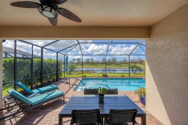 view of swimming pool with a water view, ceiling fan, a patio area, and glass enclosure