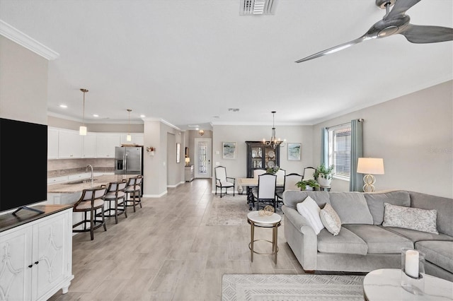 living room featuring ceiling fan with notable chandelier, sink, ornamental molding, and light wood-type flooring