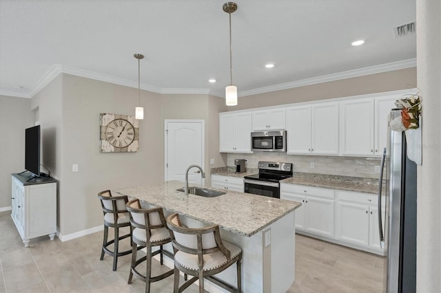 kitchen with a center island with sink, appliances with stainless steel finishes, hanging light fixtures, white cabinets, and sink