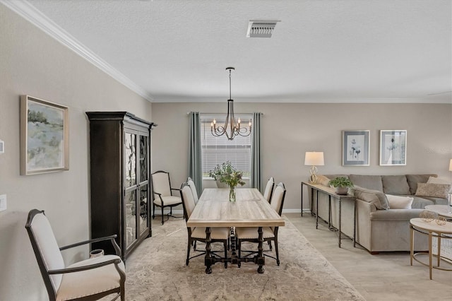 dining area with a textured ceiling, a chandelier, ornamental molding, and light wood-type flooring