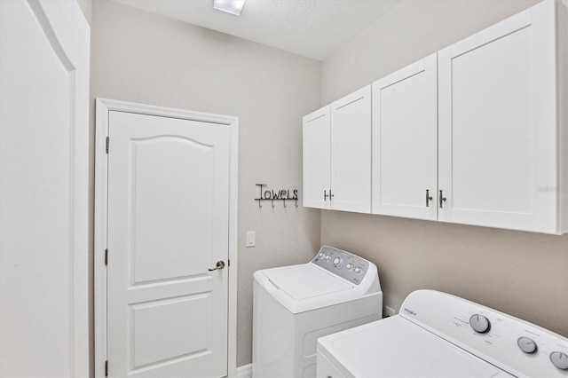 washroom featuring washing machine and dryer, cabinets, and a textured ceiling