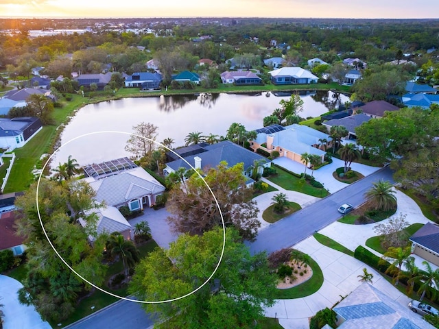 aerial view at dusk with a water view and a residential view