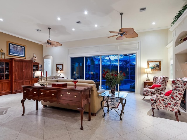 living room with light tile patterned floors, visible vents, arched walkways, ceiling fan, and ornamental molding