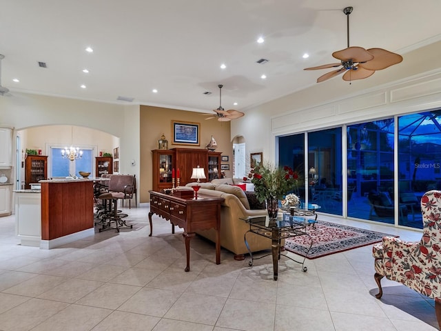 living room with arched walkways, light tile patterned floors, visible vents, ornamental molding, and ceiling fan with notable chandelier