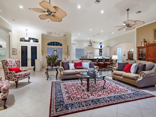 living area featuring arched walkways, french doors, light tile patterned floors, and ornamental molding