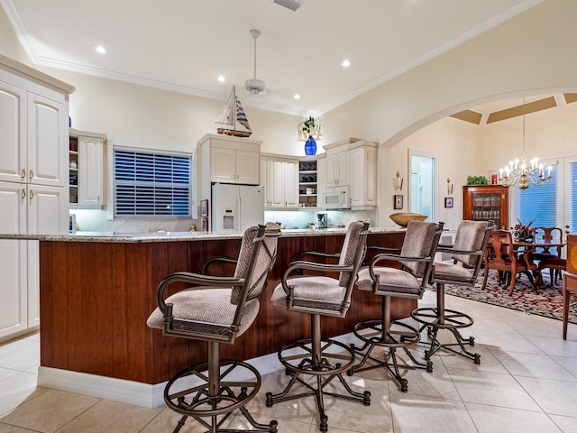 kitchen with white appliances, a large island, light stone counters, and a kitchen breakfast bar