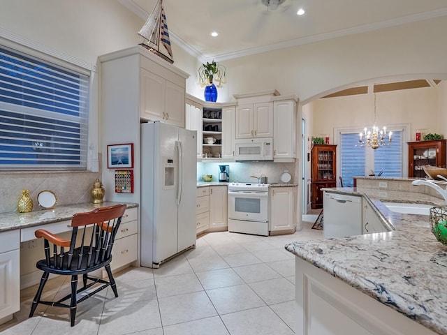 kitchen featuring white appliances, arched walkways, decorative light fixtures, white cabinetry, and a sink