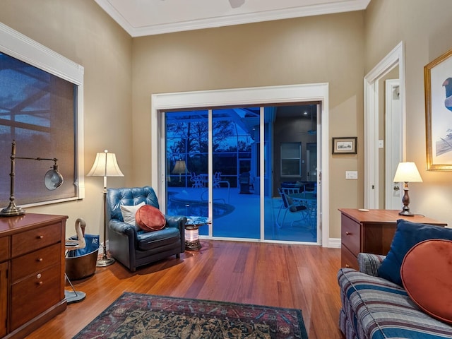 sitting room featuring ornamental molding, baseboards, and wood finished floors