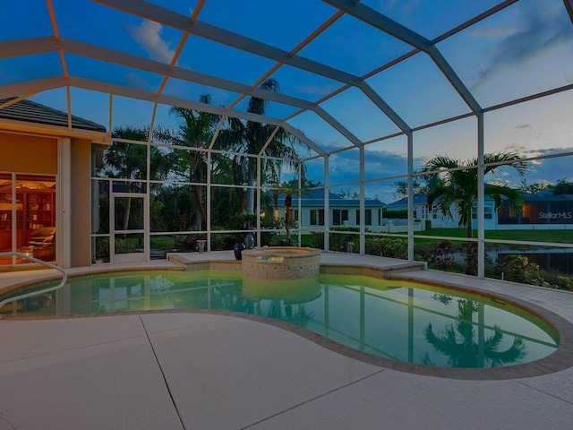 pool at dusk with a patio area, a lanai, and an in ground hot tub