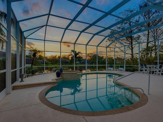 pool at dusk featuring a lanai, a patio, and an in ground hot tub