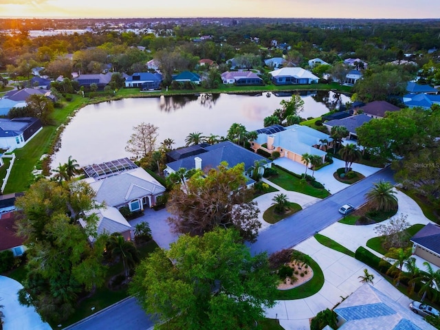 aerial view at dusk featuring a water view and a residential view