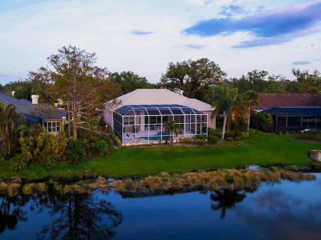 rear view of property with a water view, a lawn, and a lanai