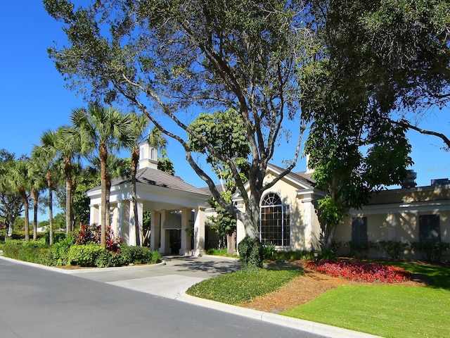 view of front of house with a front yard, concrete driveway, and stucco siding