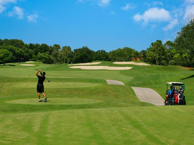 view of home's community with view of golf course and a lawn