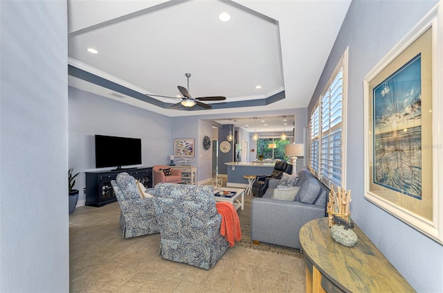 living room featuring ceiling fan, light tile patterned floors, crown molding, and a tray ceiling