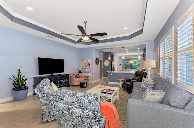 tiled living room featuring a raised ceiling, crown molding, and ceiling fan