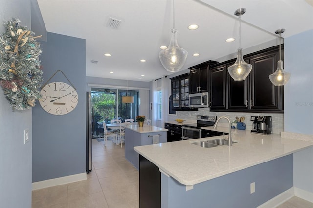 kitchen with kitchen peninsula, decorative backsplash, stainless steel appliances, sink, and pendant lighting