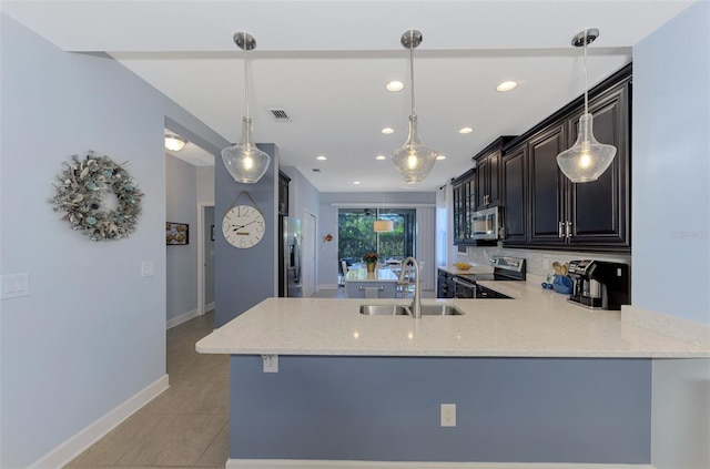 kitchen with kitchen peninsula, appliances with stainless steel finishes, sink, light tile patterned floors, and pendant lighting