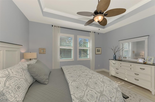 bedroom featuring a tray ceiling, light hardwood / wood-style flooring, ceiling fan, and crown molding