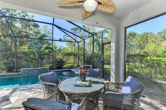 view of swimming pool with glass enclosure, ceiling fan, and a patio