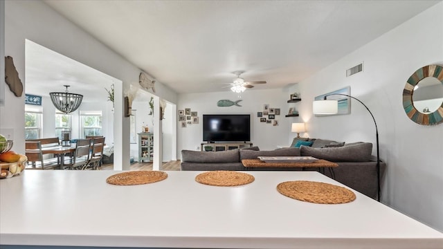 living room with ceiling fan with notable chandelier