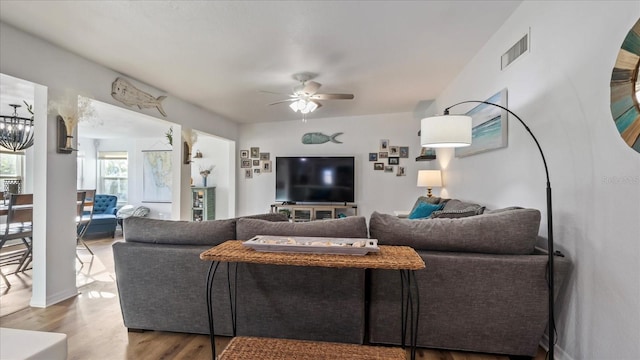 living room featuring ceiling fan with notable chandelier and hardwood / wood-style flooring