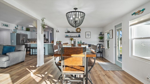 dining area with light hardwood / wood-style flooring and an inviting chandelier