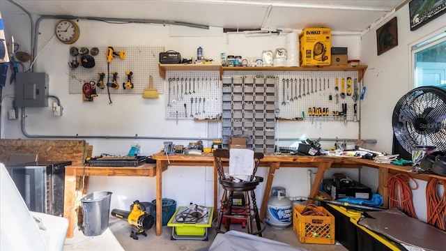 miscellaneous room with a workshop area, concrete flooring, and electric panel