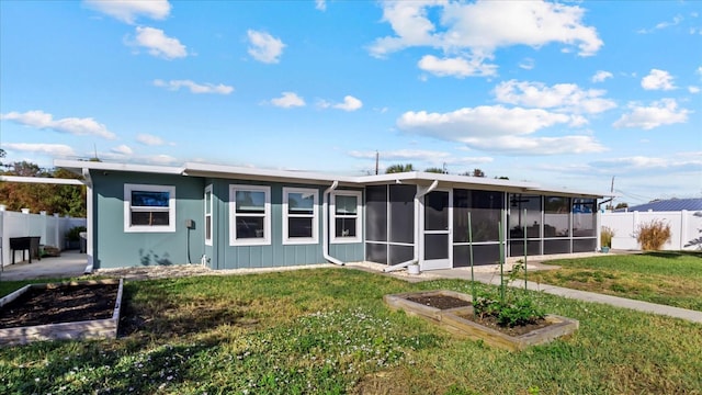 rear view of property with a yard and a sunroom