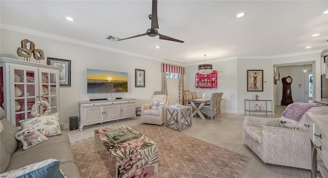 living room with light hardwood / wood-style floors, ceiling fan, and crown molding