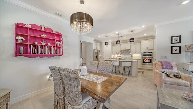 dining room with sink, light hardwood / wood-style flooring, a chandelier, and ornamental molding