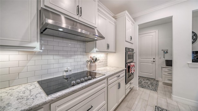 kitchen with tasteful backsplash, light stone counters, black electric cooktop, crown molding, and white cabinets