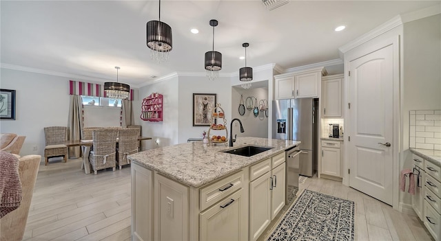 kitchen with backsplash, sink, an island with sink, and pendant lighting