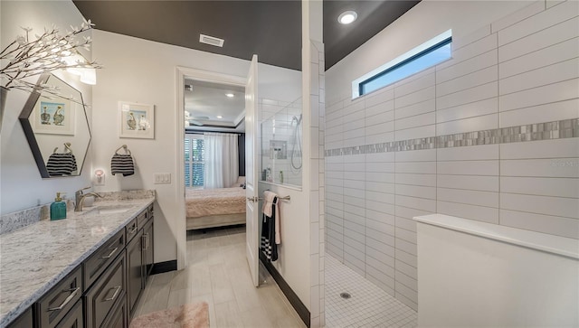 bathroom featuring hardwood / wood-style flooring, vanity, tiled shower, and a wealth of natural light