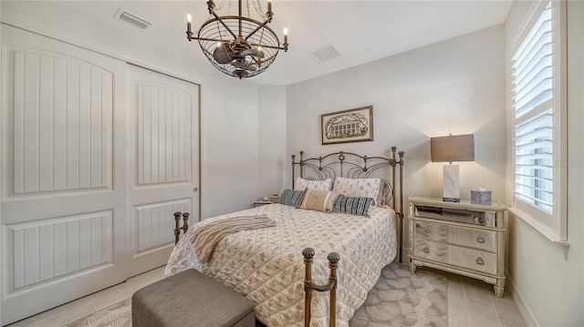 bedroom featuring light wood-type flooring, a closet, an inviting chandelier, and multiple windows