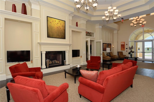 living room with a chandelier, light wood-type flooring, a towering ceiling, and crown molding