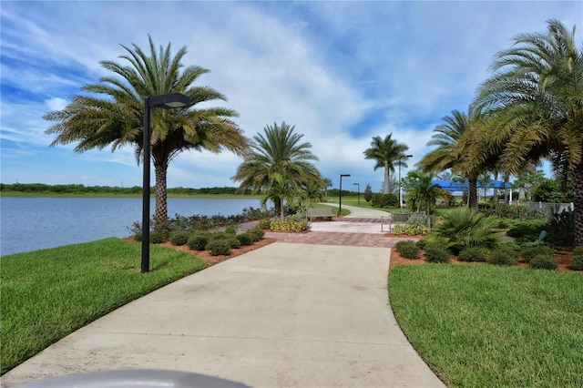 surrounding community with a water view and a lawn