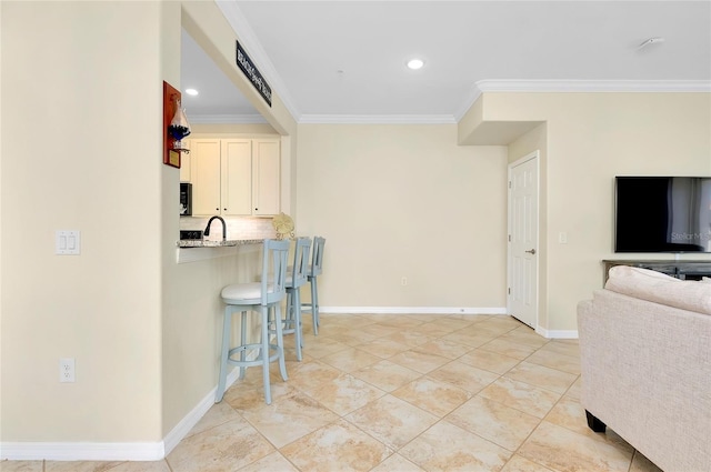 kitchen with a kitchen breakfast bar, light stone counters, and ornamental molding