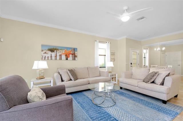 living room with ceiling fan with notable chandelier and ornamental molding