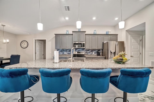 kitchen with sink, tasteful backsplash, a kitchen breakfast bar, appliances with stainless steel finishes, and decorative light fixtures