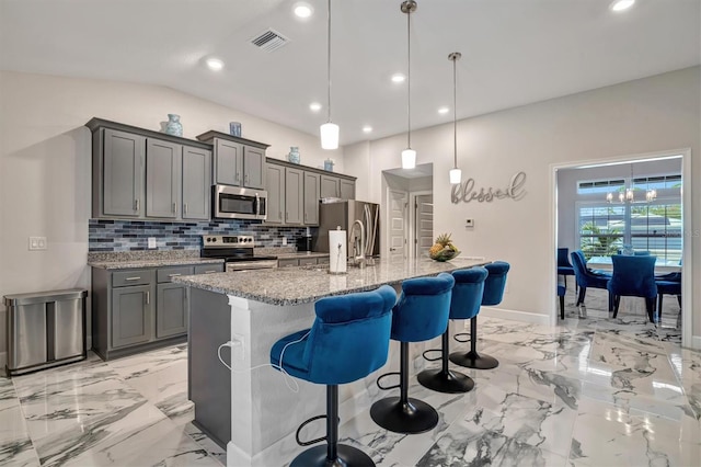 kitchen with gray cabinets, tasteful backsplash, decorative light fixtures, and stainless steel appliances