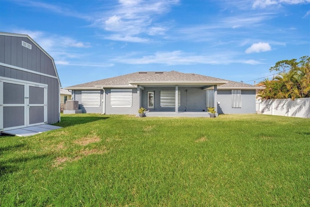 rear view of house with central air condition unit, a patio area, a lawn, and a storage unit