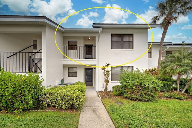 view of front facade with a balcony and a front yard