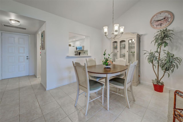 tiled dining space featuring a chandelier and vaulted ceiling