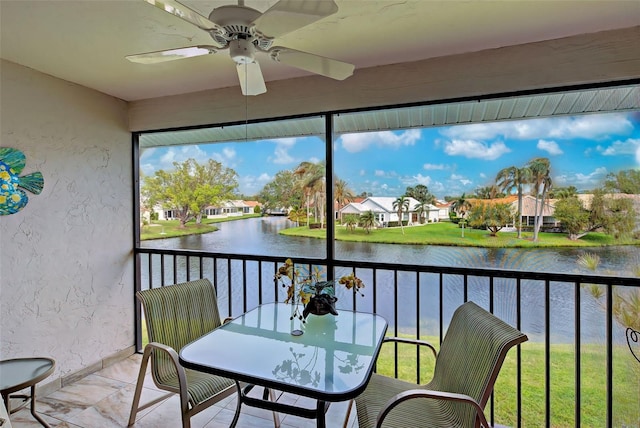 sunroom / solarium with a healthy amount of sunlight, a water view, and ceiling fan